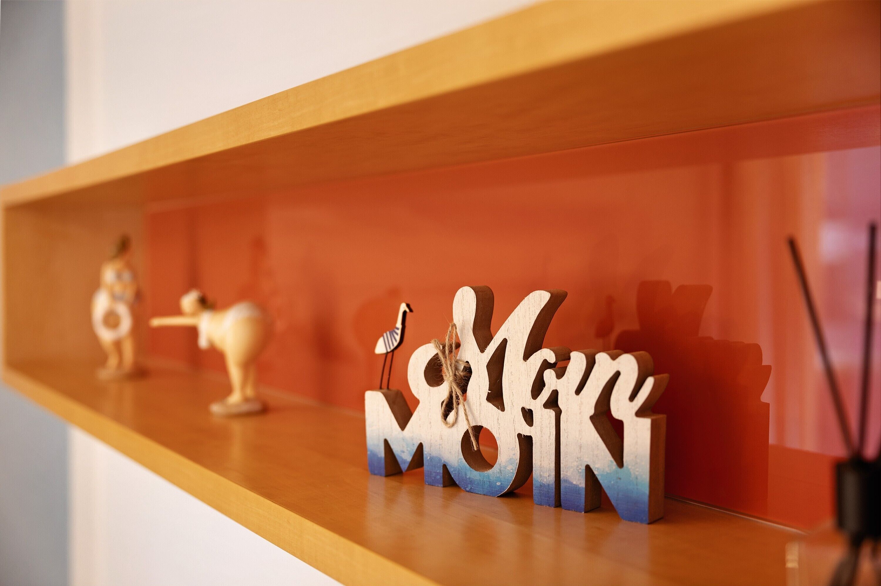 A wooden shelf with decorative items including a bird figure and the letters 'M' and 'N'.