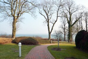 A paved pathway in a park with trees and a view of the sea. - Cliff Apartment with Private Terrace and Wi-Fi (Lübeck Travemünde)