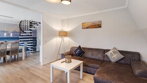 Un salon moderne avec un escalier, un coin repas et une vue sur la mer.