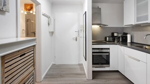 Une cuisine moderne avec des meubles blancs, un four encastré et un évier en acier inoxydable.