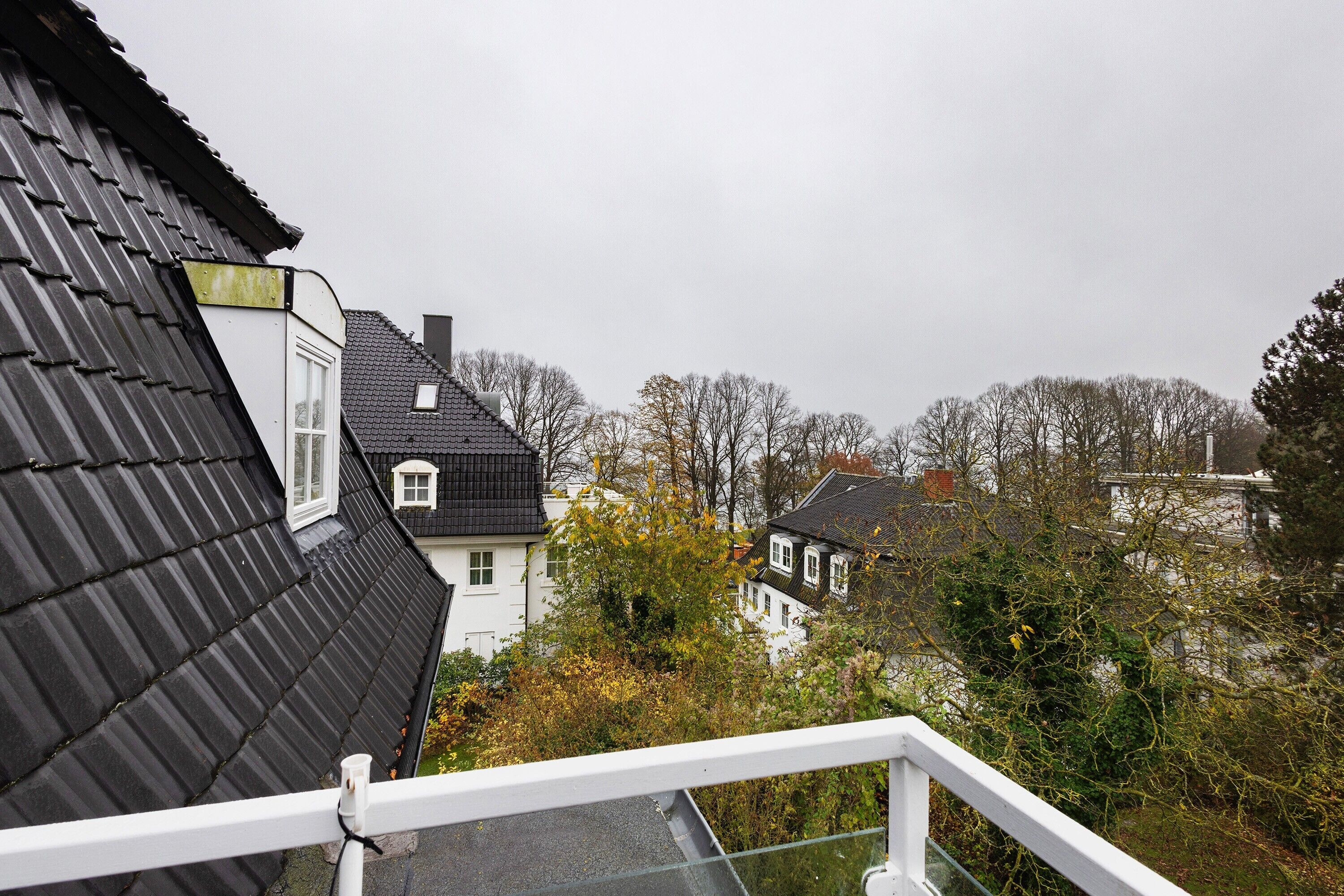 A residential area with houses, a balcony, and a view of trees and other buildings.