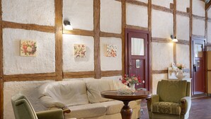 Una habitación con techo de madera, un sofá blanco, una mesa redonda y dos sillones.
