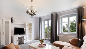 Un salon moderne comprenant un téléviseur, un canapé, une table basse et un lustre.