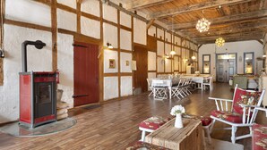 A spacious room with a wooden ceiling, a fireplace, a dining area with a table and chairs, and a seating area with a bench and chairs.