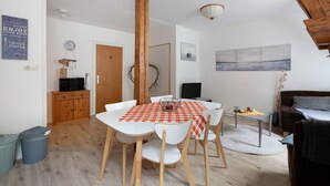Ein Essbereich mit Holztisch, weißen Stühlen und einer rot-weißen karierten Tischdecke.
