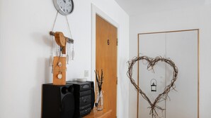 Ein Zimmer mit einem Holzkasten, einer Uhr, einer Tür mit der Nummer 6 und einem herzförmigen Schmuckstück.