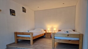 A room with two wooden beds, a small desk, and a nightstand with lamps. - Apartment 'Wattwurm' with Wi-Fi (Ahrenviölfeld)