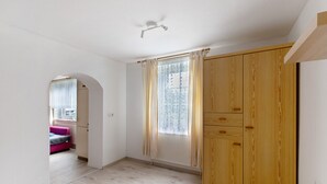 A room with a wooden wardrobe, a window with curtains, a pink sofa, and a radiator. - Apartment 'Wattwurm' with Wi-Fi (Ahrenviölfeld)