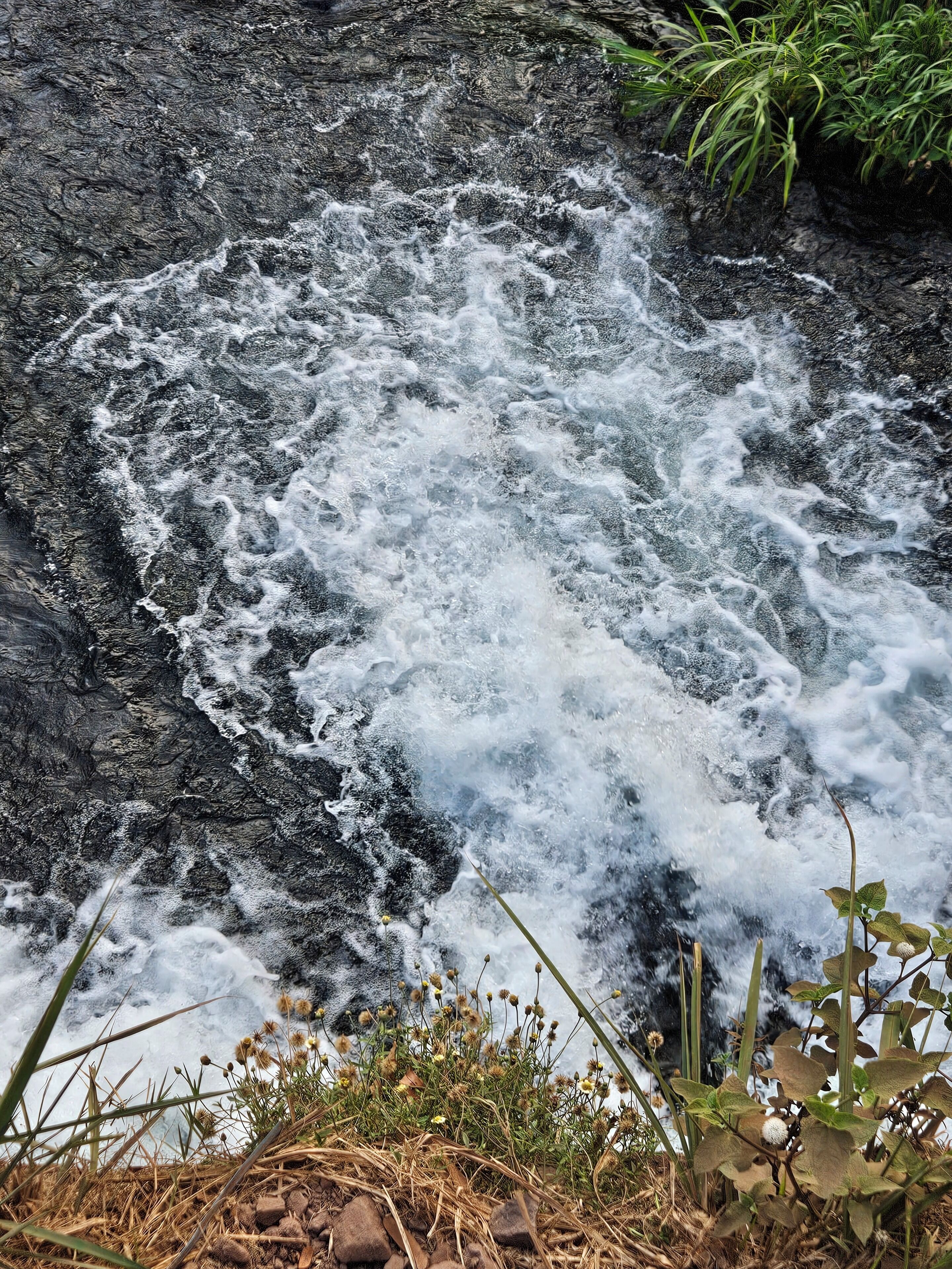 Un cours d’eau naturel qui serpente sur des rochers, entouré de végétation.