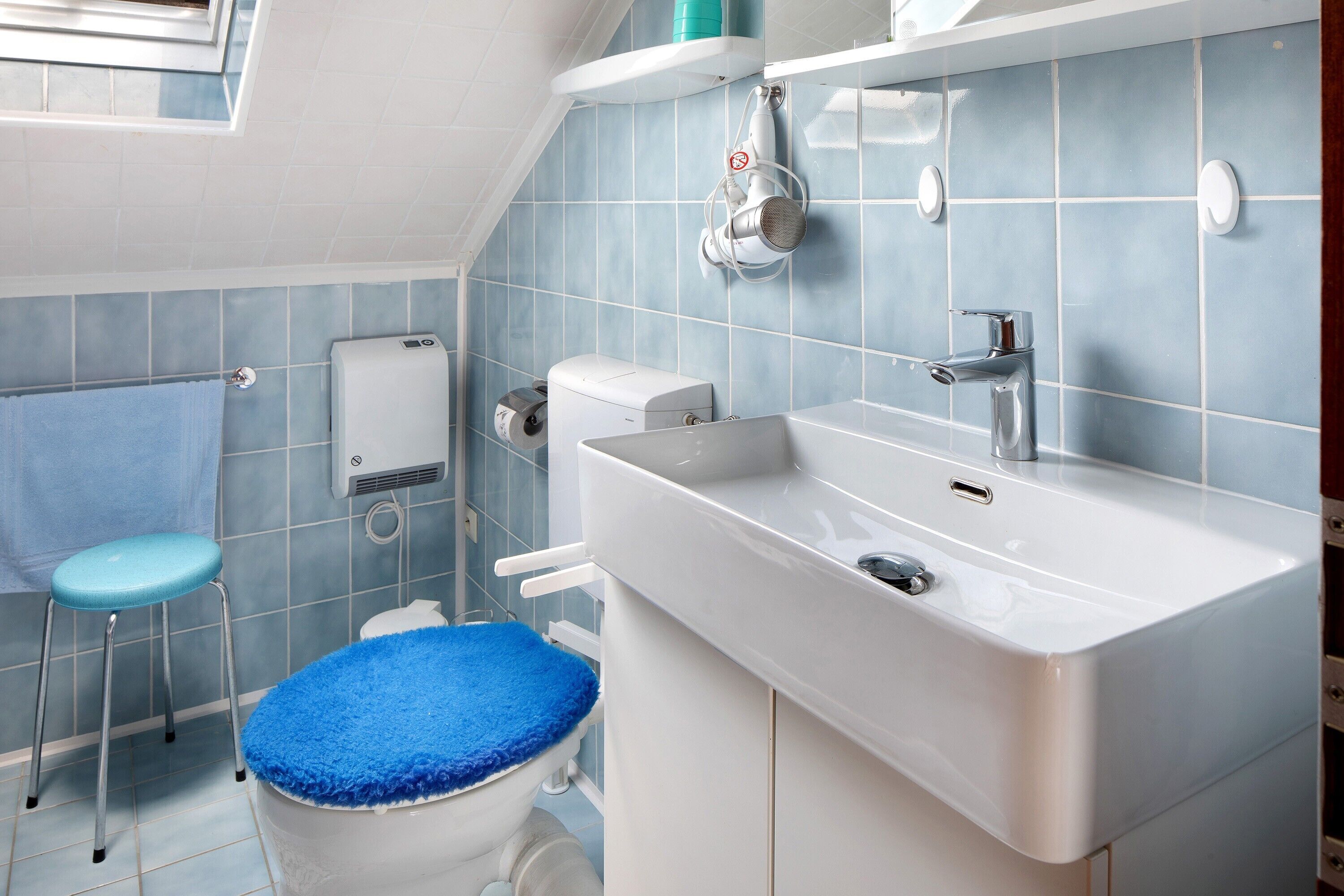 Ein Badezimmer mit Toilette, Waschbecken, Dusche und Fenster.