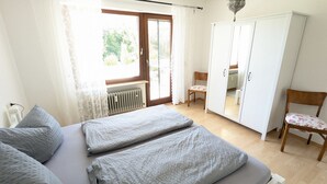 A bedroom with a bed, a chair, a wardrobe, and a radiator.