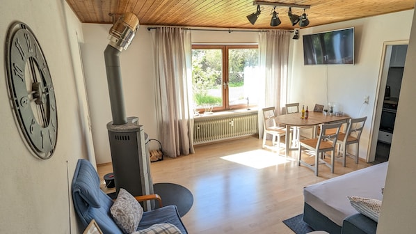 Un salon chaleureux avec une cheminée, un coin repas et un téléviseur fixé au mur.