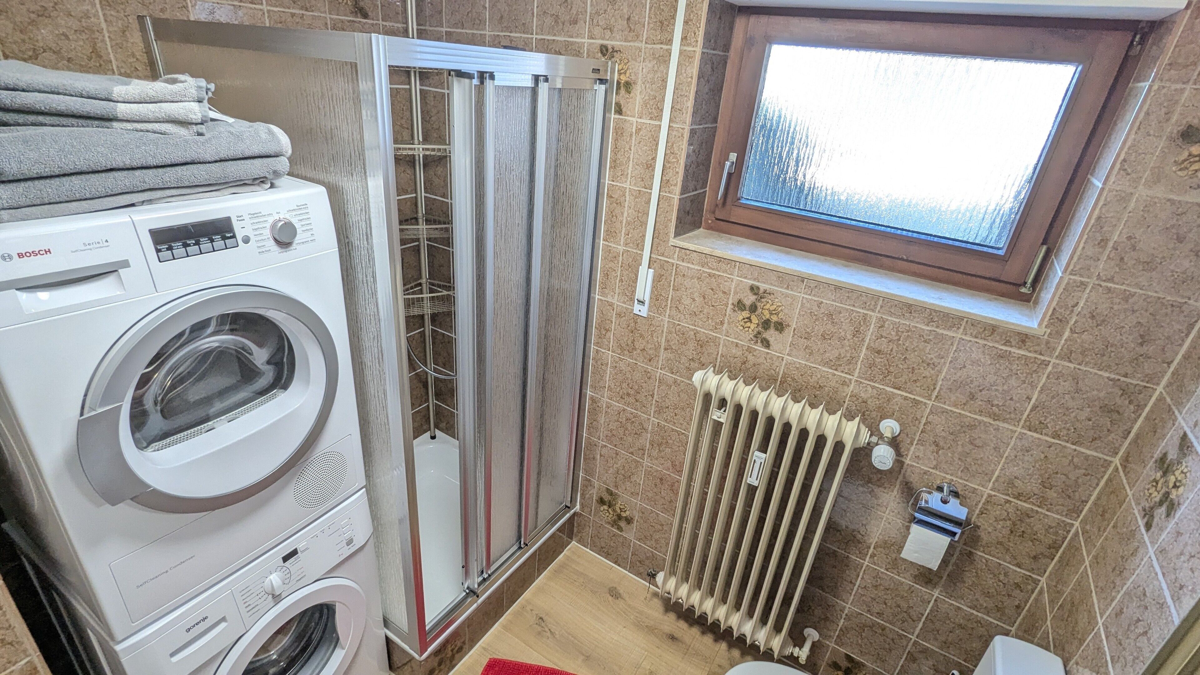 A laundry area with a Bosch washing machine, a dryer, and a radiator.