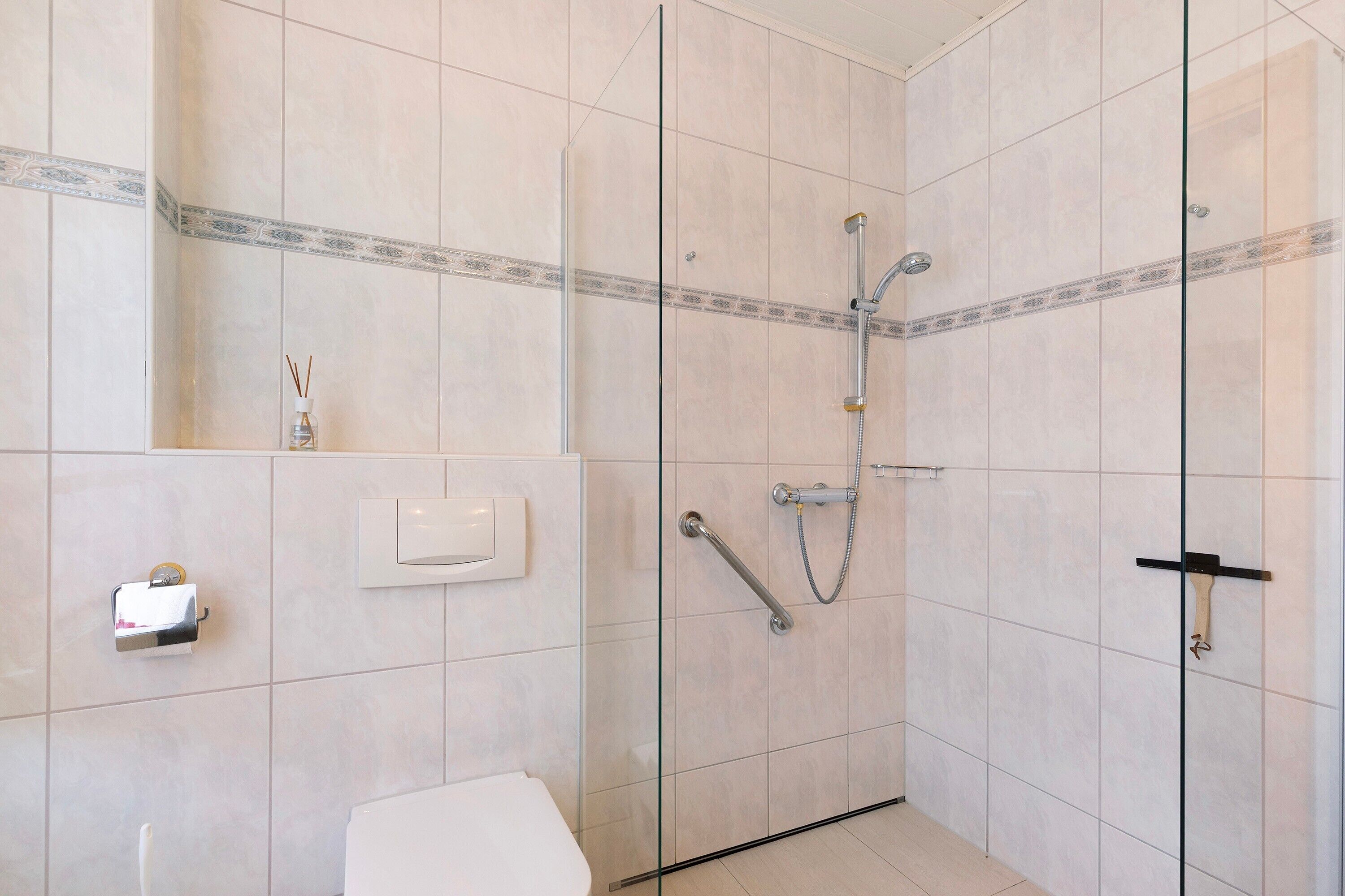 Une salle de bain avec une douche à parois de verre, des toilettes et un sèche-mains.