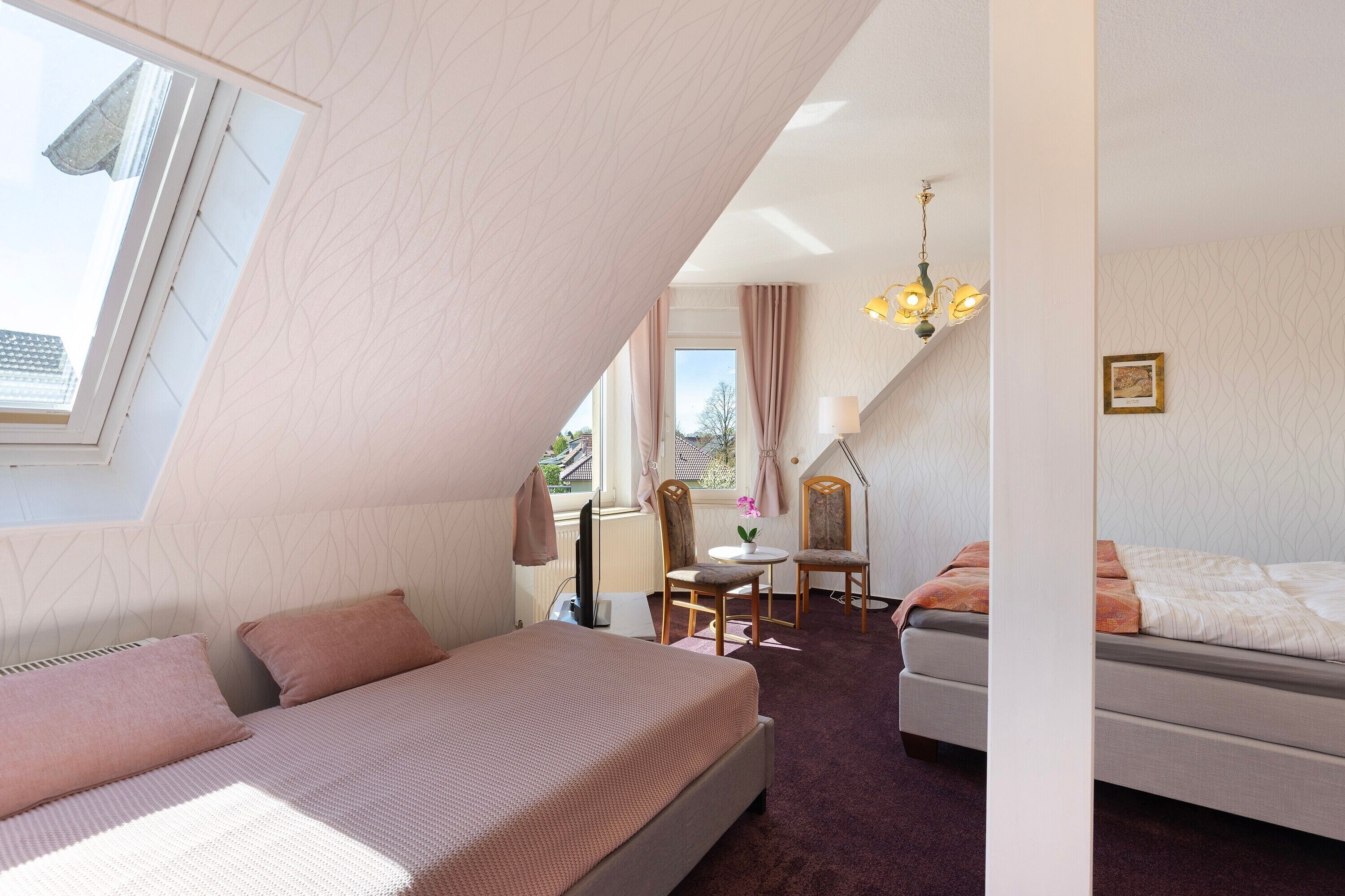 A bedroom with a bed, a desk, and a chair, and a window with curtains.