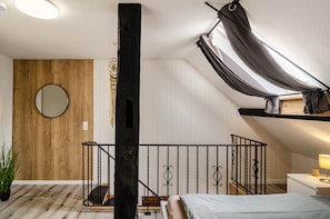 A bedroom with a sloped ceiling, a round mirror, a bed, a small table with a lamp, and a potted plant. - Apartment 'Didi' with Shared Terrace, Shared Garden and Wi-Fi (Detern)