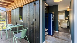A wooden deck with a table and chairs, a kitchen area with a blue refrigerator, and a door leading to a room.