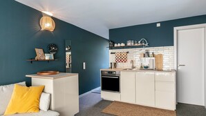 A compact kitchen with white cabinetry, a built-in oven, and a coffee machine.