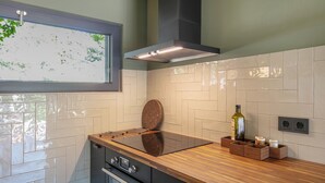 Una cocina con estufa integrada, encimera de madera y ventana con vistas a árboles.
