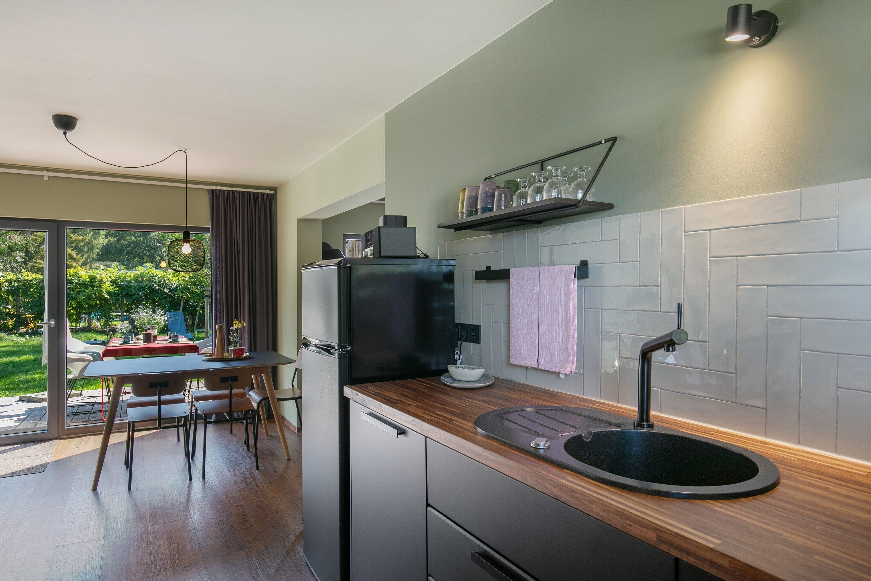 Une cuisine moderne équipée d’un four encastré, d’un évier et d’un coin repas avec une table et des chaises.