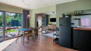 Une cuisine moderne avec un coin repas, de grandes fenêtres et une vue sur l’extérieur.