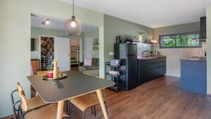 Une cuisine moderne avec un coin repas, un plancher en bois et une vue sur l’extérieur.