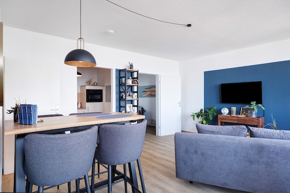Un espace de vie moderne comprenant une cuisine, un coin repas et un mur d’accent bleu.
