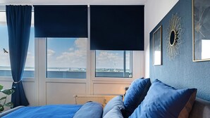 A bedroom with a bed, curtains, a radiator, and a view of the cityscape. - Apartment 'Clara' with Sea View, Balcony and Wi-Fi (Bremerhaven)