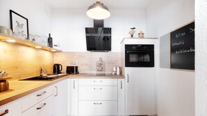 A modern kitchen with white cabinets, a wooden countertop, a black oven, and a chalkboard with writing. - Apartment 'Clara' with Sea View, Balcony and Wi-Fi (Bremerhaven)