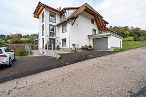 Une maison à deux étages avec un garage, une allée et une voiture garée.