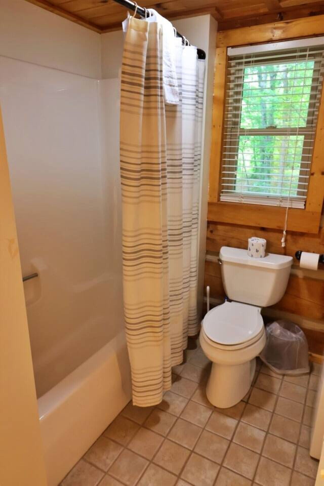 A bathroom with a bathtub, toilet, and shower curtain.