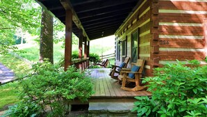 A wooden cabin with a porch, number 226, surrounded by greenery.