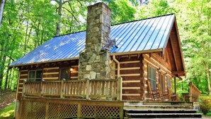 A log cabin with a stone chimney, wooden deck, and a metal roof, surrounded by trees. - The Hilltop: 6 Minutes to Hiking, Casino & Golf (Whittier)
