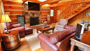 A cozy cabin interior with a stone fireplace, leather furniture, and a wooden staircase. - The Hilltop: 6 Minutes to Hiking, Casino & Golf (Whittier)