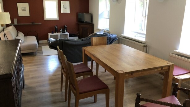 Ein Wohnzimmer mit einem Holzesstisch, zwei Sofas, einem Fernseher und einer Heizung.