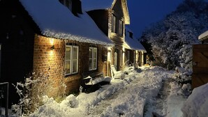Ein mit Schnee bedecktes Haus mit Ziegelaußenwänden und Schornstein.