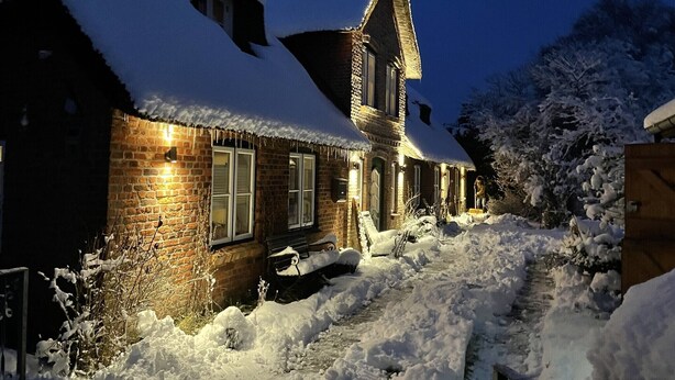Una casa cubierta de nieve con fachada de ladrillo y una chimenea.