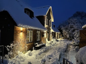 A snow-covered house with a brick exterior and a chimney.