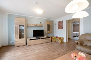 A living room with a TV, wooden cabinets, a sofa, and a coffee table.