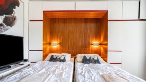 Una habitación de hotel con dos camas, un televisor y un cabecero de madera.