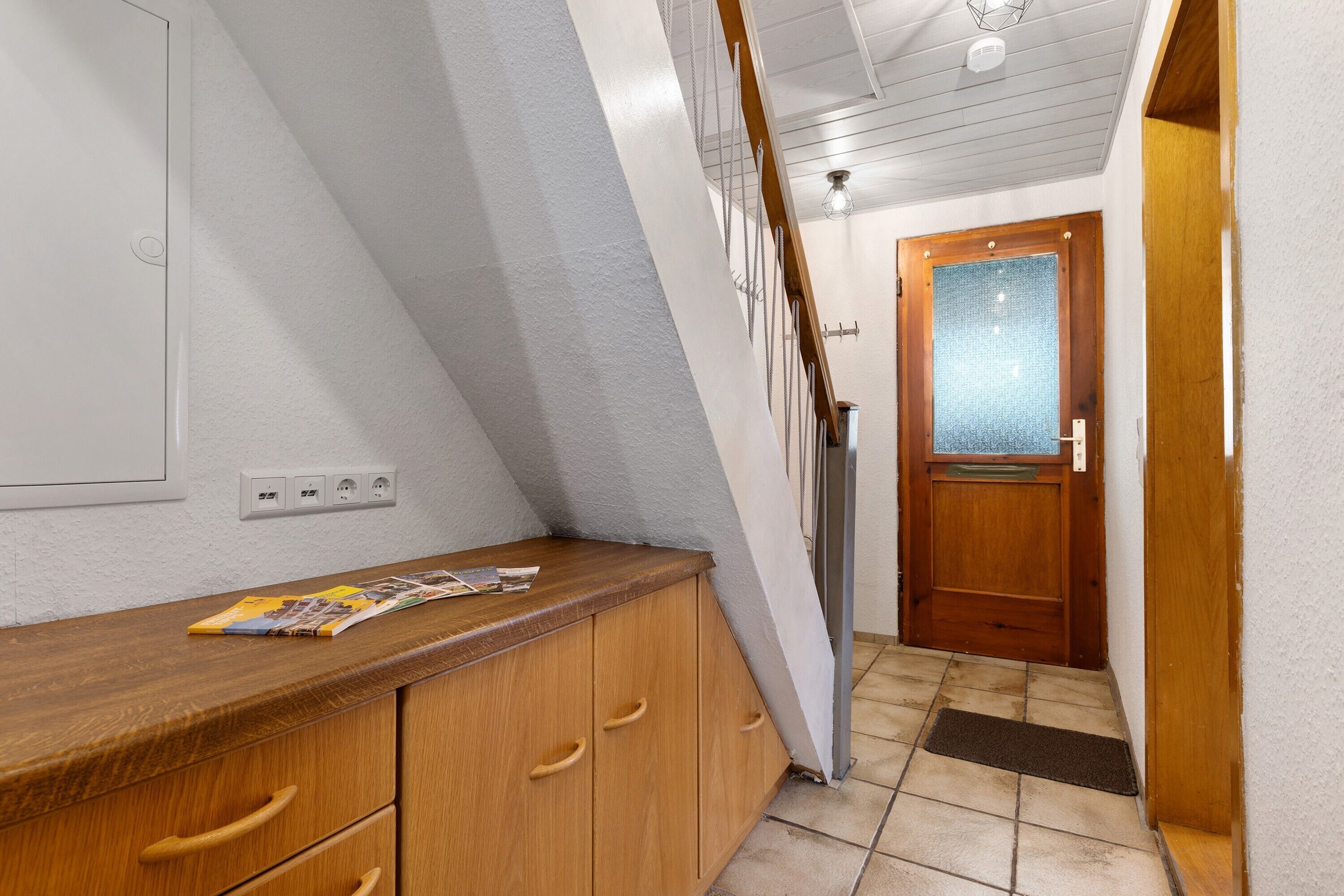 A hallway with a wooden counter, a door with frosted glass, and a tiled floor.