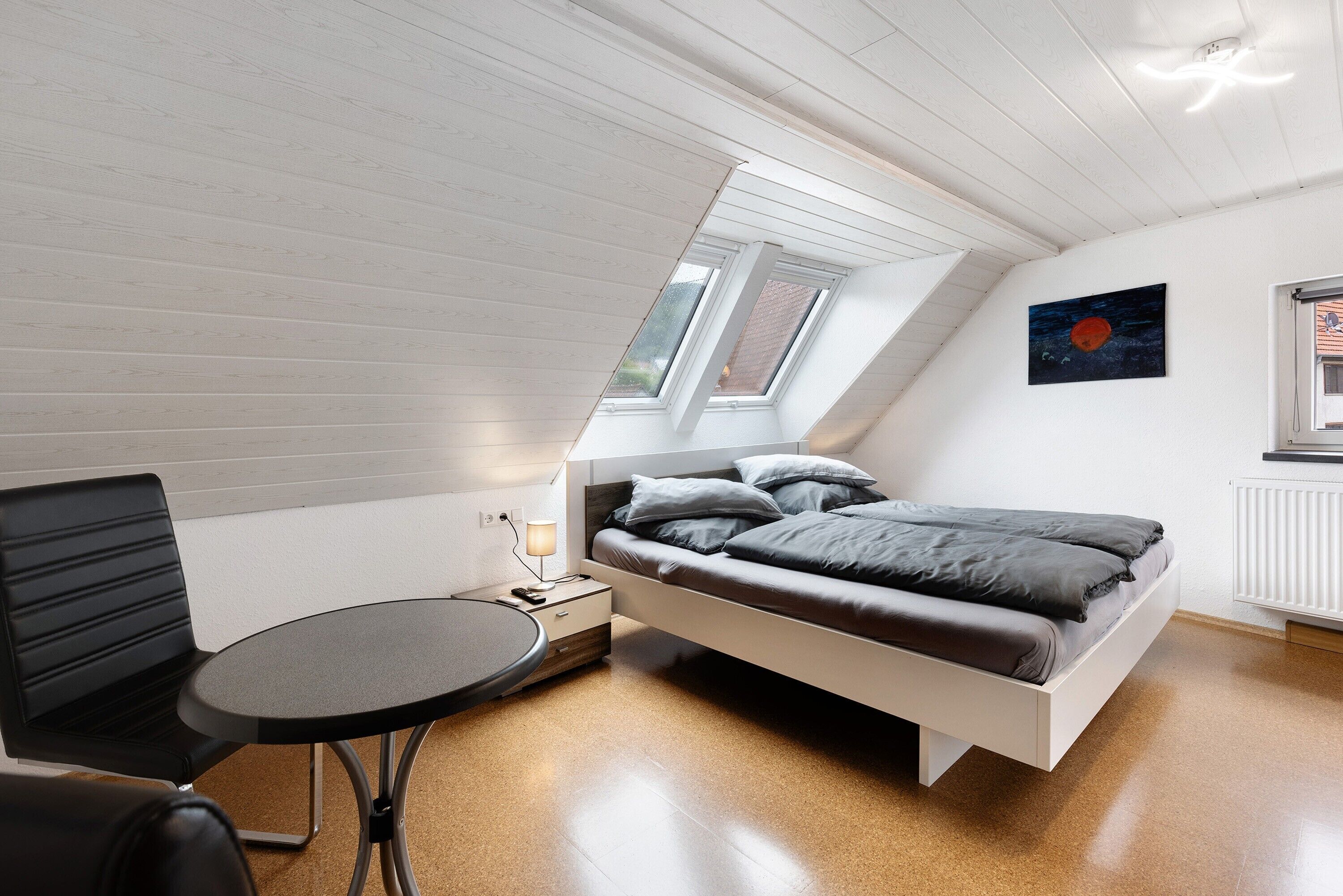 A modern loft bedroom with a bed, a small table, and a chair.