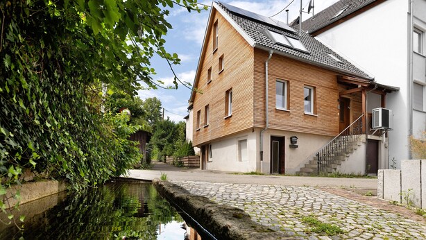 Una casa de madera con un patio empedrado y un estrecho canal de agua.