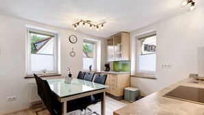 Una cocina moderna con comedor, un reloj y una ventana con persianas.