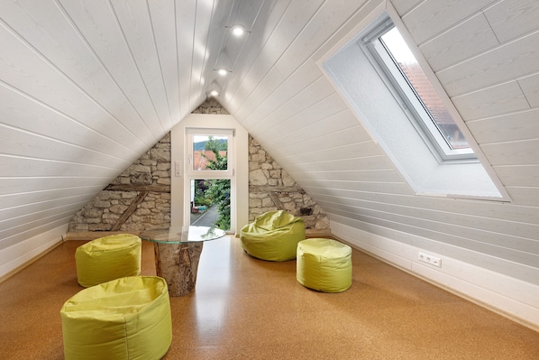 Une pièce avec un plafond en pente, un mur en pierre, une porte en verre et des fauteuils en forme de haricot vert.