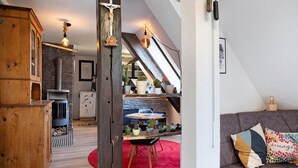 Uma sala de estar aconchegante com um tapete vermelho, móveis de madeira e uma escada que leva a um andar superior.