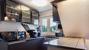 Uma cozinha compacta com armários escuros, uma pia de aço inoxidável e um micro-ondas.