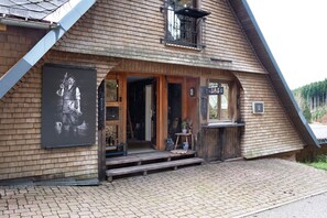 Un bâtiment en bois doté d’un toit en pente, d’un balcon et d’une porte donnant sur l’intérieur.