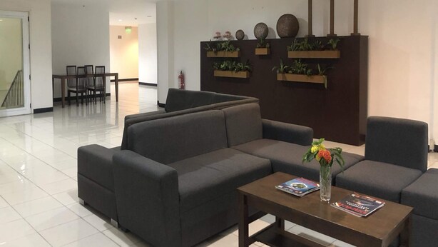 Een moderne lobby met een hoekbank, een salontafel en een receptiebalie.