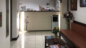 Een receptiegedeelte met een balie, een koelkast, een automaat en een zithoek met tijdschriften.